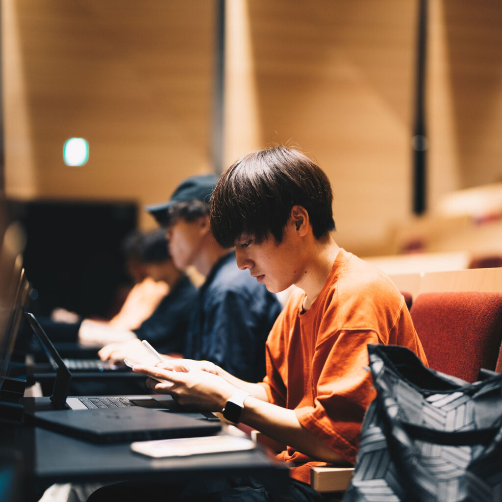 大教室でノートパソコンに向き合う学生の写真